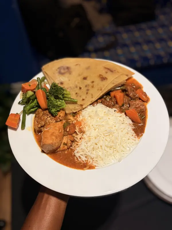 A plated meal of chapati, stew, rice and vegetables
